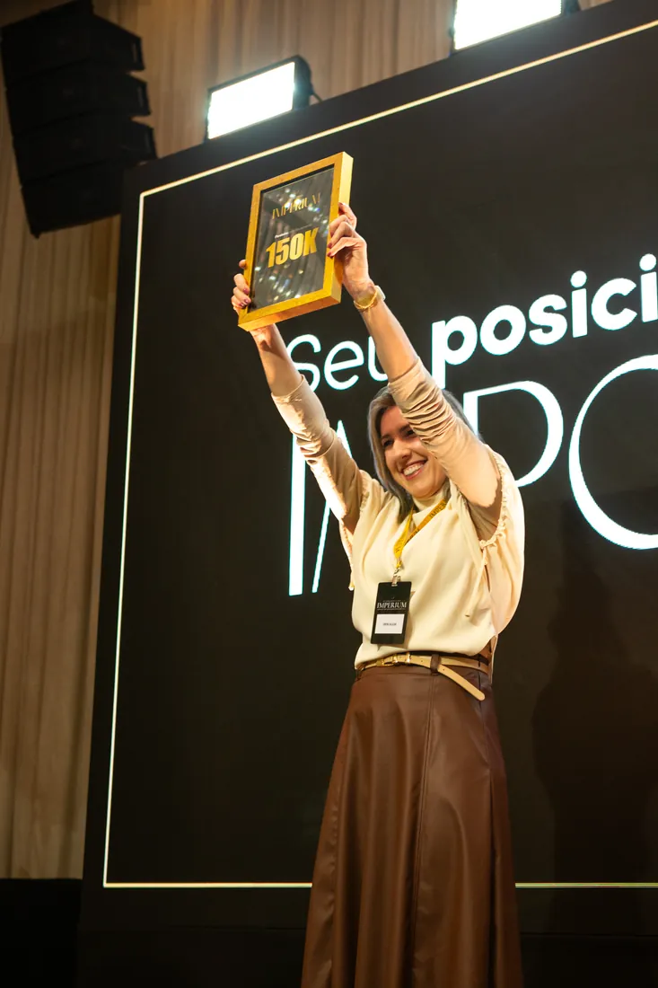 Mentorada comemorando com a placa de faturamento erguida