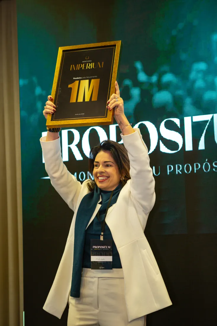 Mentorada comemorando com a placa de R$ 1 milhão erguida