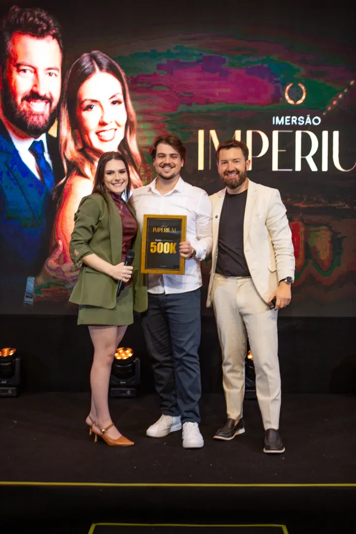 Mentorados com placa de faturamento no palco da Imersão Imperium